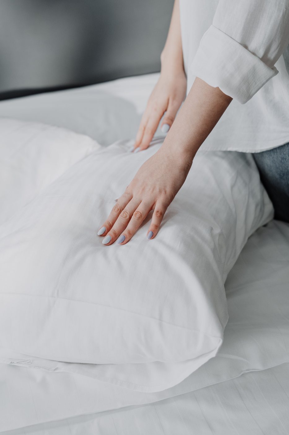 Hand smoothing crisp white hotel bedsheet and pillow